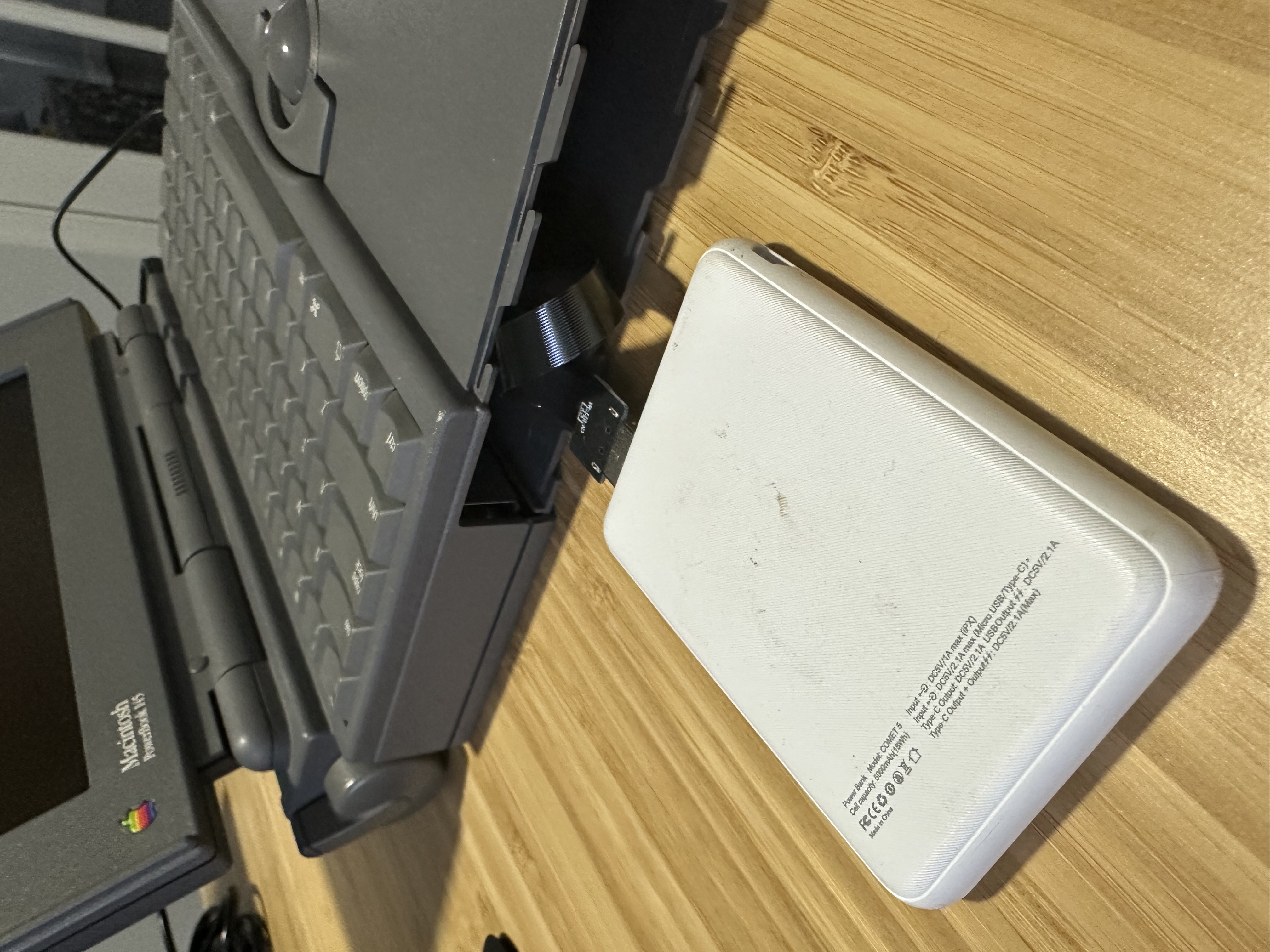 Flat USB cable routed toward the PowerBook battery bay for external BlueSCSI power